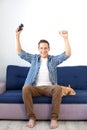 The concept of the game. the guy is playing a video game with a joystick at home with a dog. A smiling man in a shirt, sitting on Royalty Free Stock Photo