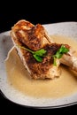 The concept of Georgian cuisine. Half a baked chicken in garlic sauce with crispy crust on a white plate, on a black background Royalty Free Stock Photo