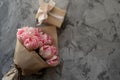 Concept gift beloved woman on holiday. Beautiful bouquet of pink tulips on a gray background. Wrap the box in kraft paper