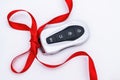 Concept And Gift Idea. Flat Lay Smart Car Key With A Red Gift Ribbon On A White Background. Electronics, Spare Parts And Car