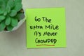 Concept of Go The Extra Mile It\'s Never Crowded write on sticky notes isolated on Wooden Table Royalty Free Stock Photo