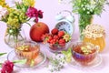 The concept of a good summer morning. Cups of tea among bouquets of wild flowers, strawberries in a cup, jars of jam, apples,