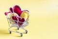 Concept grocery basket with colored hearts on a yellow background.