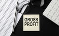 Concept GROSS PROFIT message on sticker with glasses,chart and calculator on the black background