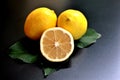 Concept of a group of lemons, two whole and one half on black background