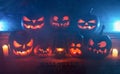 The concept of Halloween. Many Evil Scary Pumpkins in the dark with a blue ice glow. Jack Lantern amidst the darkness with a bat