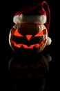 The concept of Halloween and the New Year and Christmas. The evil scary pumpkin Santa in the Santa Claus hat in the dark with ref Royalty Free Stock Photo