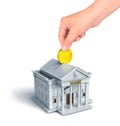 Concept of a hand throwing golden coin in a piggy bank looks like classical bank building