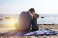 Dad and son are sitting on the beach and chatting. A boy with a father on the background of the sea and sunset cuddling. The