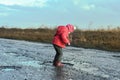 Concept - happy childhood. Little girl plays in puddle, children`s fun, unforgettable moments, dirty and wet shoes, fun with fath Royalty Free Stock Photo