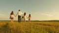 Concept of a happy childhood. mother, father and little daughter with sisters walking in field in the sun. Happy young Royalty Free Stock Photo