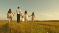 Concept of a happy childhood. mother, father and little daughter with sisters walking in field in the sun. Happy young Royalty Free Stock Photo