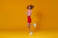 Concept happy emotional young woman in red jumping on yellow background