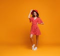 Concept happy emotional young woman in red summer dress and hat jumping on yellow background