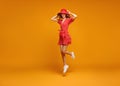 Concept happy emotional young woman in red summer dress and hat jumping   on yellow background Royalty Free Stock Photo