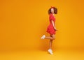 Concept happy emotional young woman in red summer dress jumping on yellow background