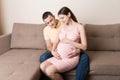 Concept happy family in anticipation of the birth of a baby. Pregnant woman and her husband cuddling on the sofa at home Royalty Free Stock Photo