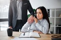 Concept harassment. Afraid young woman sit at table. Harrasment goes out of her boss. He keep hand on her shoulder. Guy Royalty Free Stock Photo