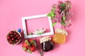 The concept of harvesting in the summer.Jars of jam, strawberries in a cup, cherries in a blue cup, a bouquet of flowers on a pink Royalty Free Stock Photo