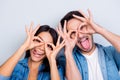 Concept of having funtime and grimacing, behaving like kids. Close up photo of two happy people making binoculars with their hand