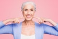 Concept of having strong healthy white perfect teeth at old age. Portrait of old lady with beaming smile pointing on her Royalty Free Stock Photo
