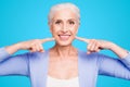 Concept of having strong healthy white perfect teeth at old age. Portrait of old lady with beaming smile pointing on her Royalty Free Stock Photo
