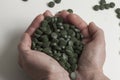The concept of health. Spirulina tablets closeup in the palms.