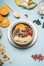 Concept of a healthy breakfast, berries, bananas, oranges, cereals, and milk in a vintage bowl on a blue background, space for tex
