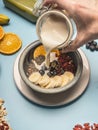 Concept of a healthy breakfast, berries, bananas, oranges, cereals, and milk in a vintage bowl on a blue background, space for tex Royalty Free Stock Photo