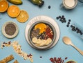 Concept of a healthy breakfast, berries, bananas, oranges, cereals, and milk in a vintage bowl on a blue background, space for tex Royalty Free Stock Photo