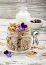 The concept of a healthy breakfast of whole wheat cereals, berries and edible flowers on a garden violet on a light Royalty Free Stock Photo