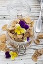 The concept of a healthy breakfast of whole wheat cereals, berries and edible flowers on a garden violet on a light Royalty Free Stock Photo