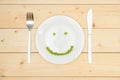 The concept of healthy eating, green peas laid out on a white plate in the shape of a smile. Top view Royalty Free Stock Photo