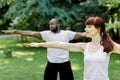 Concept of healthy family lifestyle and yoga at park. Young multiethnic couple exercising outdoors with arms Royalty Free Stock Photo