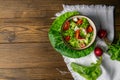 The concept of healthy kitchen. Salad of fresh herbs, radish, cucumber and tomatoes with oil on a white napkin on rustic wooden Royalty Free Stock Photo