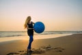 Concept of healthy lifestyle for women. Smiling young female with long blonde hair with big blue ball Royalty Free Stock Photo