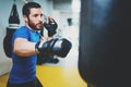 Concept of a healthy lifestyle.Young muscular man fighter practicing kicks with punching bag.Kick boxer boxing as Royalty Free Stock Photo