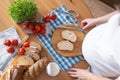 A pregnant young woman spreads curd cheese on slices of bread. View from above Royalty Free Stock Photo