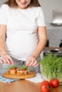 Pregnant young woman preparing healthy sandwiches with microgreens and vegetables. Food rich in fiber Royalty Free Stock Photo