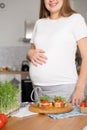 Pregnant young woman preparing healthy sandwiches with microgreens and vegetables. Food rich in fiber Royalty Free Stock Photo