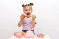 Concept of healthy and unhealthy food, little smiling blonde girl in purple T-shirt chooses between green apple and hamburger, Royalty Free Stock Photo