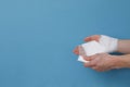 Concept of help during an injury, man wrapping hand in bandage on blue background Royalty Free Stock Photo