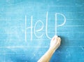 Teacher writes help on blackboard Royalty Free Stock Photo
