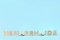 Concept of hemorrhoids with wooden letters on blue background