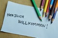 Concept of Herzlich Willkommen write on sticky notes isolated on Wooden Table Royalty Free Stock Photo