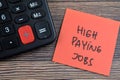 Concept of High Paying Jobs write on sticky notes isolated on Wooden Table Royalty Free Stock Photo