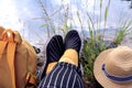 The concept of hiking in nature. Yellow backpack, feet in yellow socks and sports slippers, light summer hat on the background of