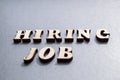 The concept of hiring workers, written by HIRING JOB in wooden letters on a gray background with selective focus and space for