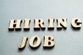 The concept of hiring workers, written by HIRING JOB in wooden letters on a gray background with selective focus and space for