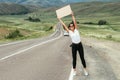 The concept of hitchhiking tourism. A traveling woman is hitchhiking on the road. A woman is hitchhiking on the road.